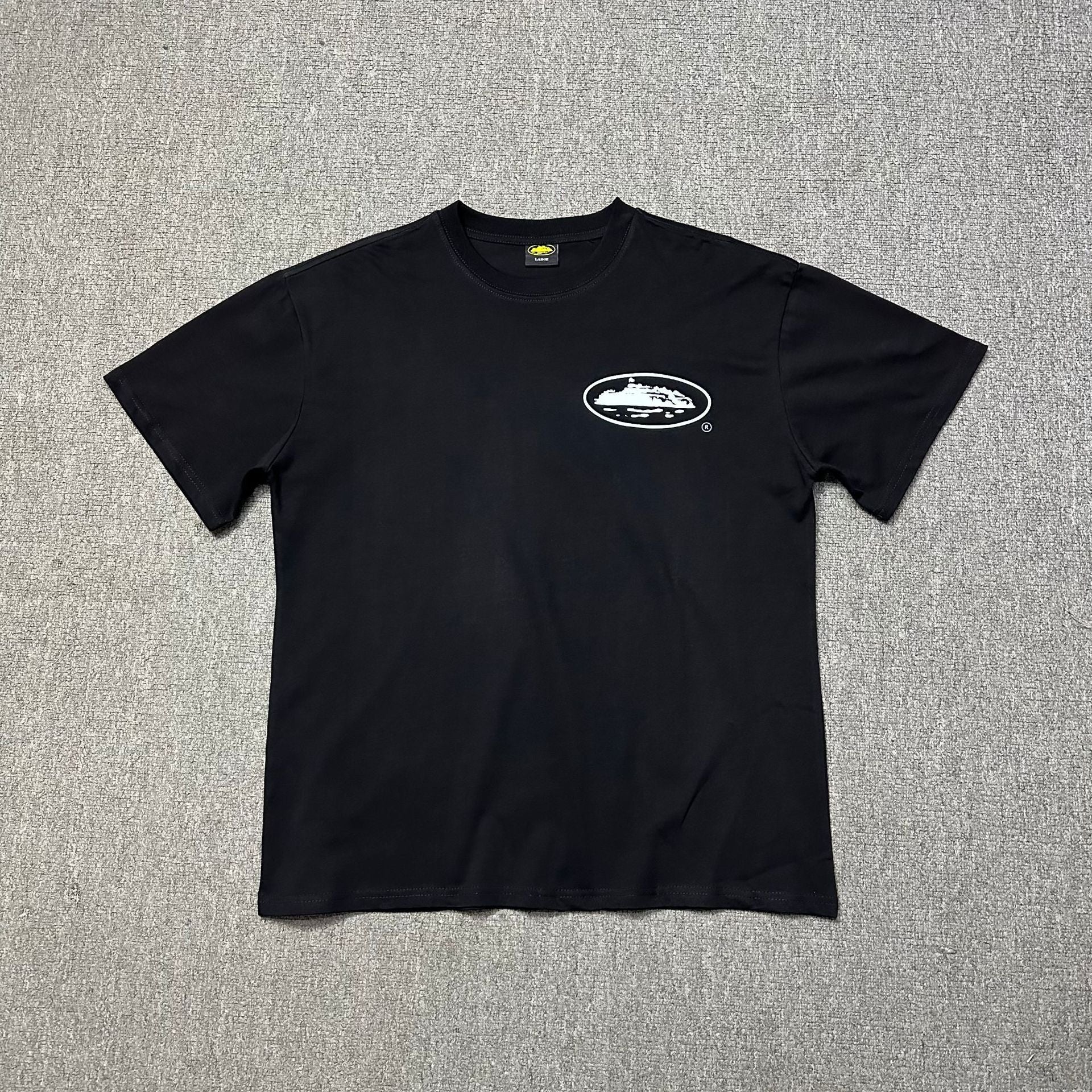 Black t-shirt with a logo on a gray textured background