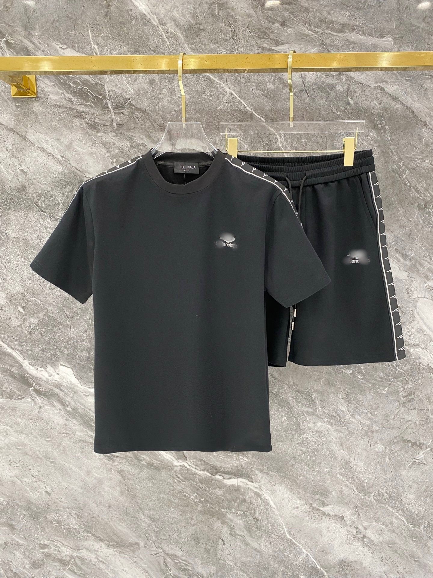 Black t-shirt and shorts set with brand logo on a marble surface