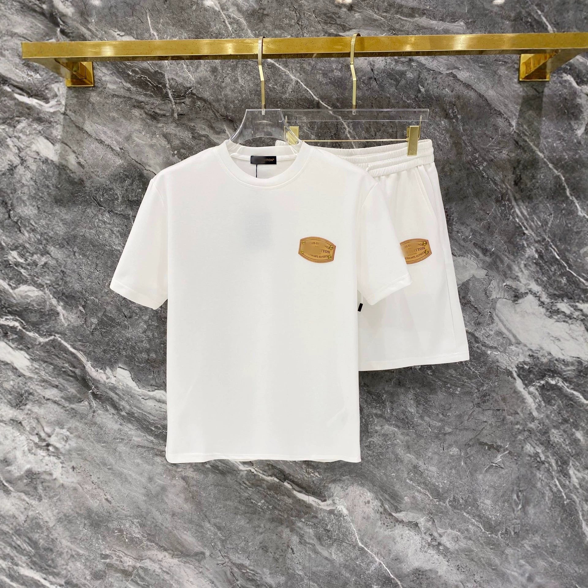 White t-shirt and shorts set with gold accents on a marble background