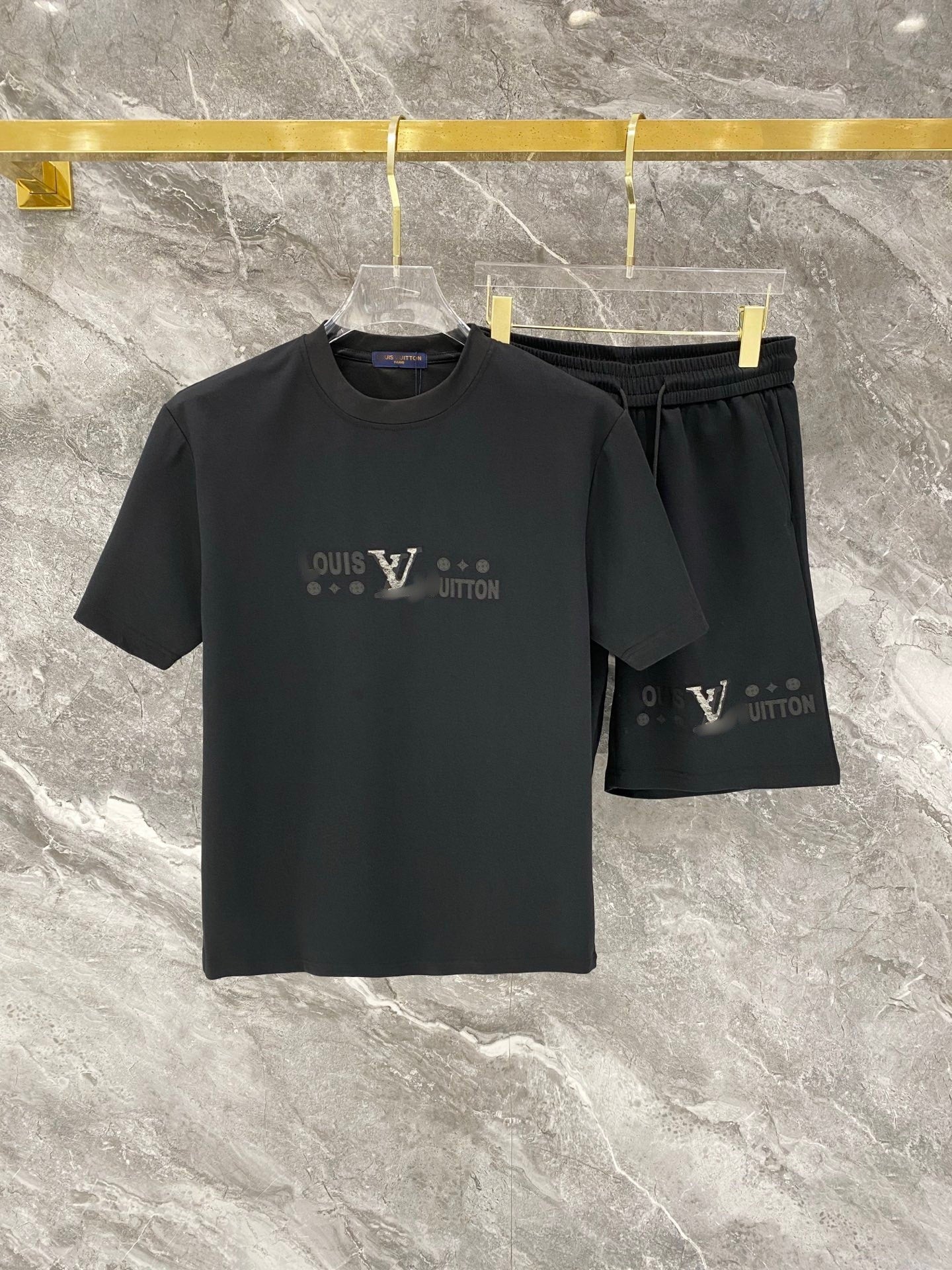 Black t-shirt and shorts set with Louis Vuitton logo on a marble surface