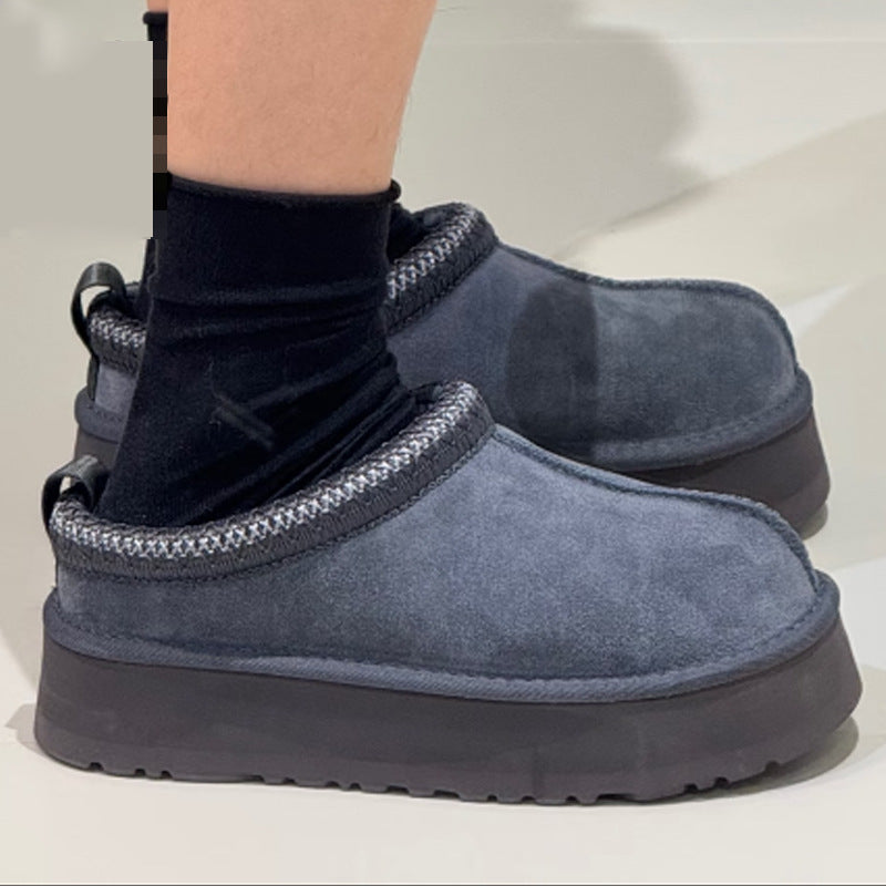 A pair of slip-on platform slippers in a muted blue-gray suede-like material, shown worn with black socks on a light neutral background.