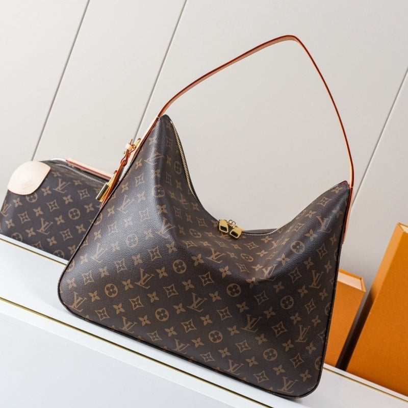 Louis Vuitton monogram canvas shoulder bag in dark brown with gold-tone hardware, displayed on a white surface with a mirror and orange boxes in the background.