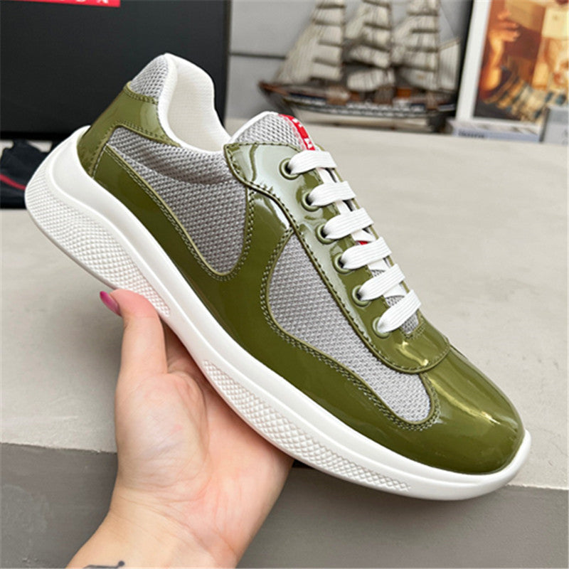 Green and gray sneaker with white laces held by a hand against a neutral background