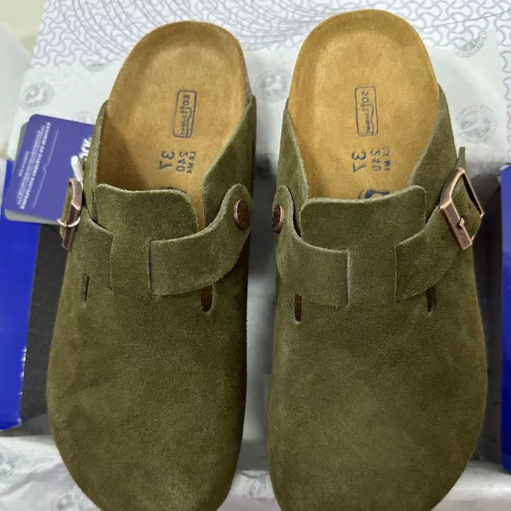 Pair of green suede clogs with buckles on a white surface
