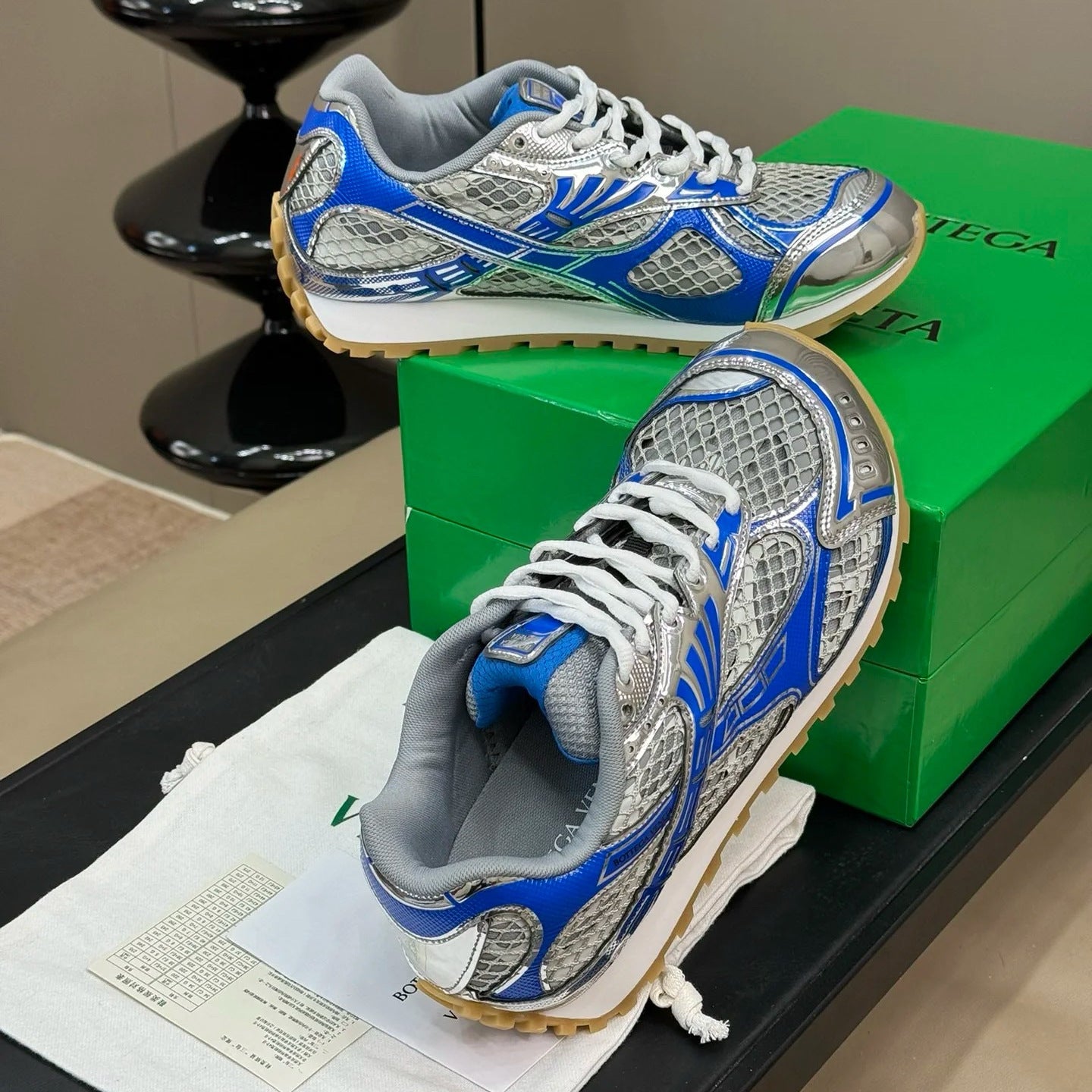 Blue and gray athletic shoes on a green box with a beige background