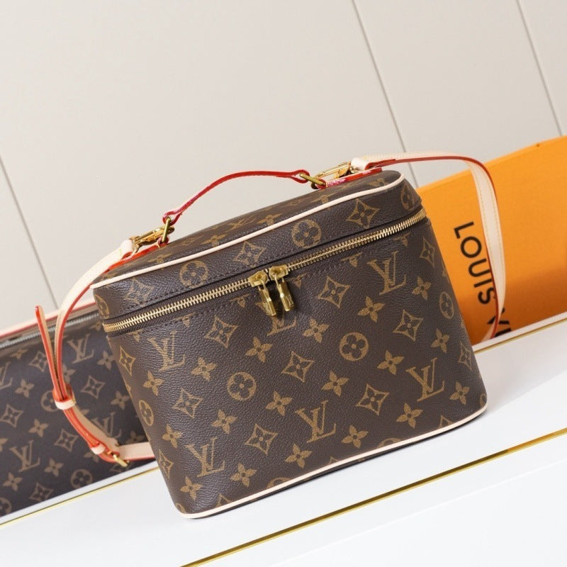 Louis Vuitton monogram canvas cosmetic bag with a top zipper, gold-tone hardware, and a red leather handle, shown alongside an orange Louis Vuitton box on a white surface.