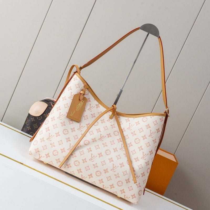 Louis Vuitton shoulder bag in beige monogram canvas with tan leather trim and strap, displayed on a white shelf with a Louis Vuitton tag hanging from the front.