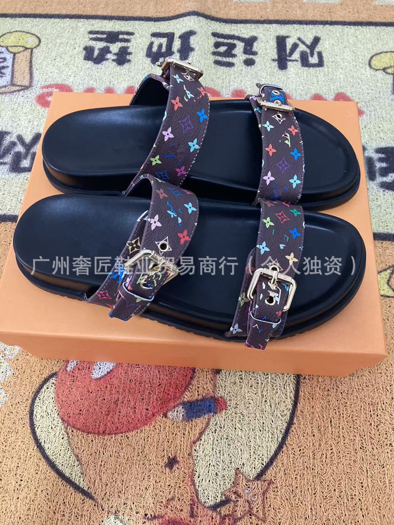 Black sandals with colorful straps on a brown surface