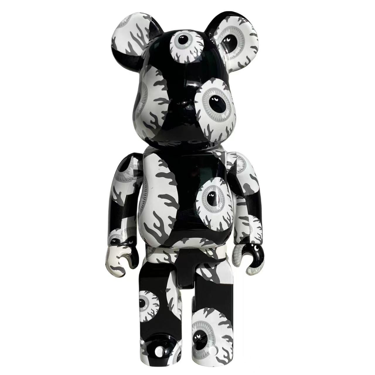 A bear-shaped collectible figure with a glossy black and white eye pattern, standing against a plain white background.