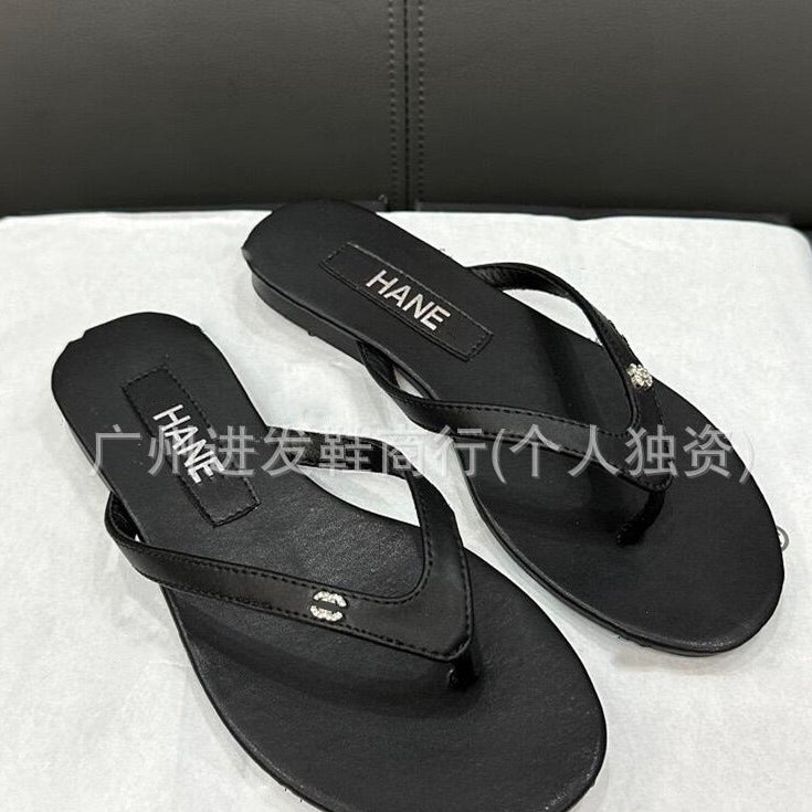 Black HANE sandals on a white towel with a dark background