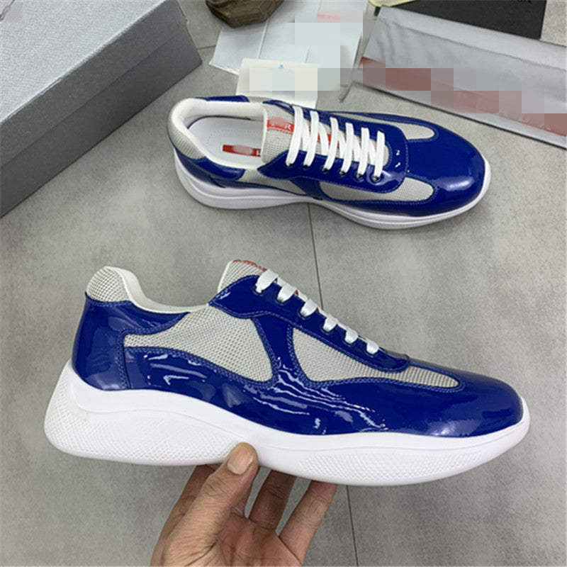 Blue and white sneakers held by a hand on a gray floor.