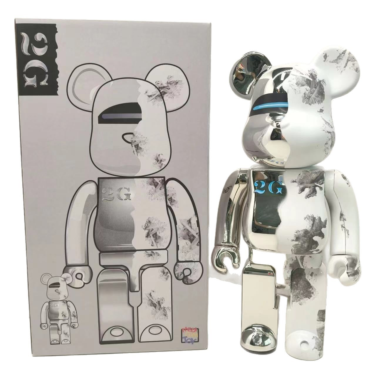 A metallic silver Bearbrick toy with black floral splatter patterns and a blue '26' on its chest, standing next to its original packaging box.