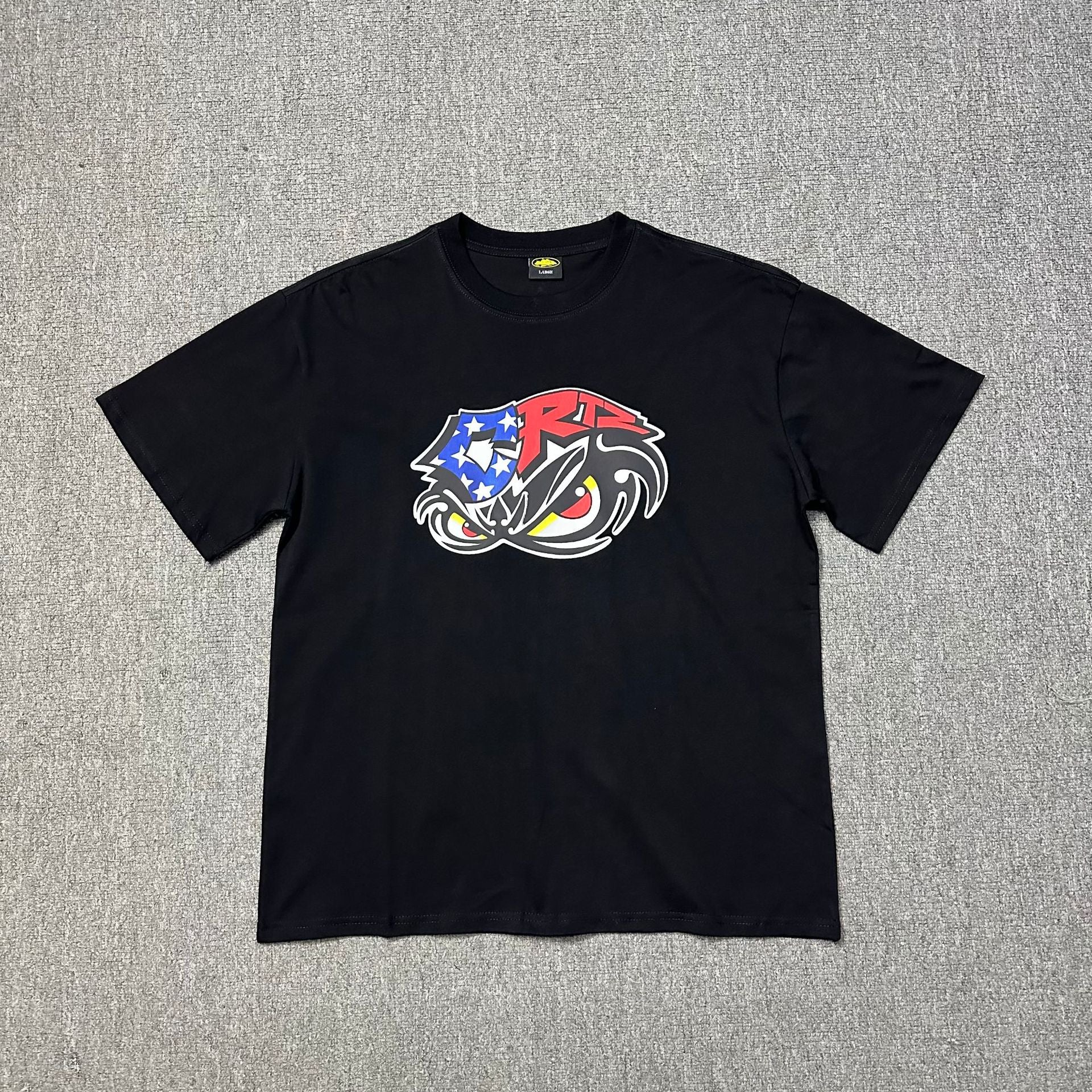 Black t-shirt with a colorful graphic design on a gray textured background
