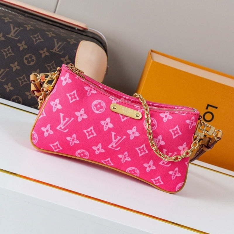 A pink Louis Vuitton monogram canvas shoulder bag with gold-tone chain straps, displayed on a white surface next to a Louis Vuitton monogram pouch and an orange Louis Vuitton box.