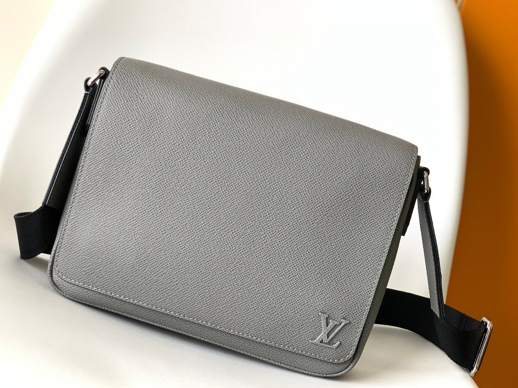 Gray leather bag with a brand logo on a white surface