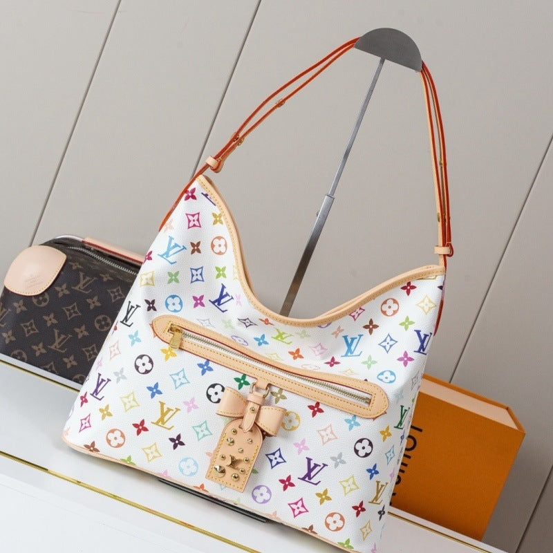 Louis Vuitton monogram shoulder bag in white canvas with multicolor printed motifs and tan leather trim, displayed on a stand with a Louis Vuitton box in the background.
