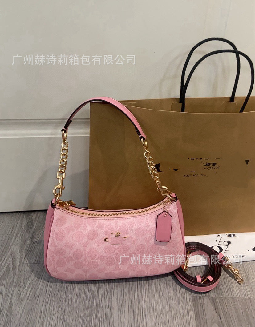 Pink handbag with gold chain and strap on a wooden surface