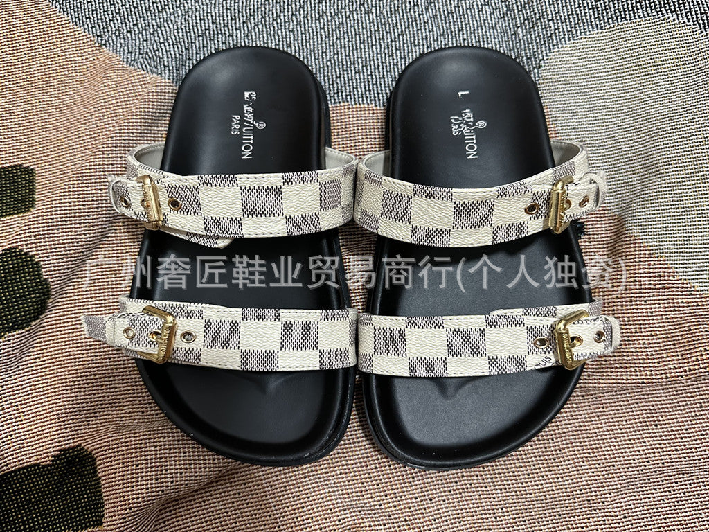Pair of black sandals with checkered straps on a textured surface