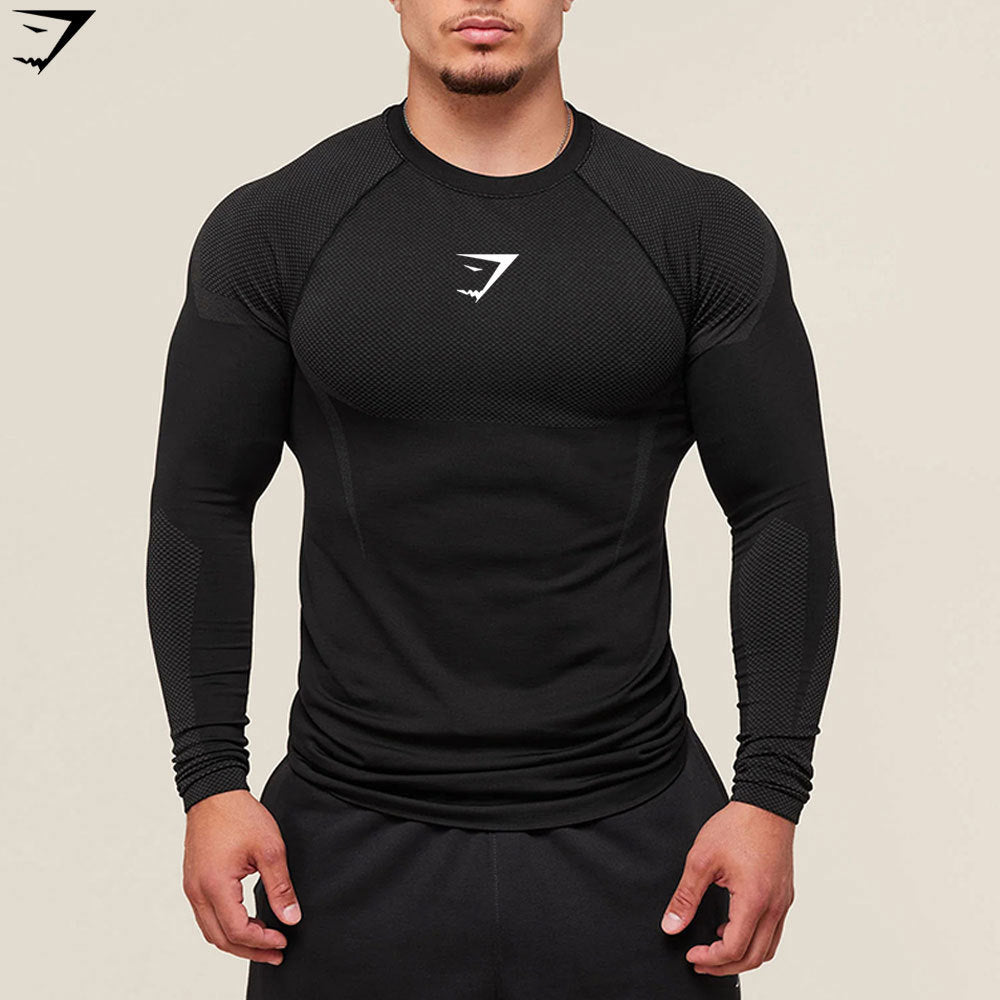 Person wearing a black long-sleeve athletic shirt with a logo on a beige background