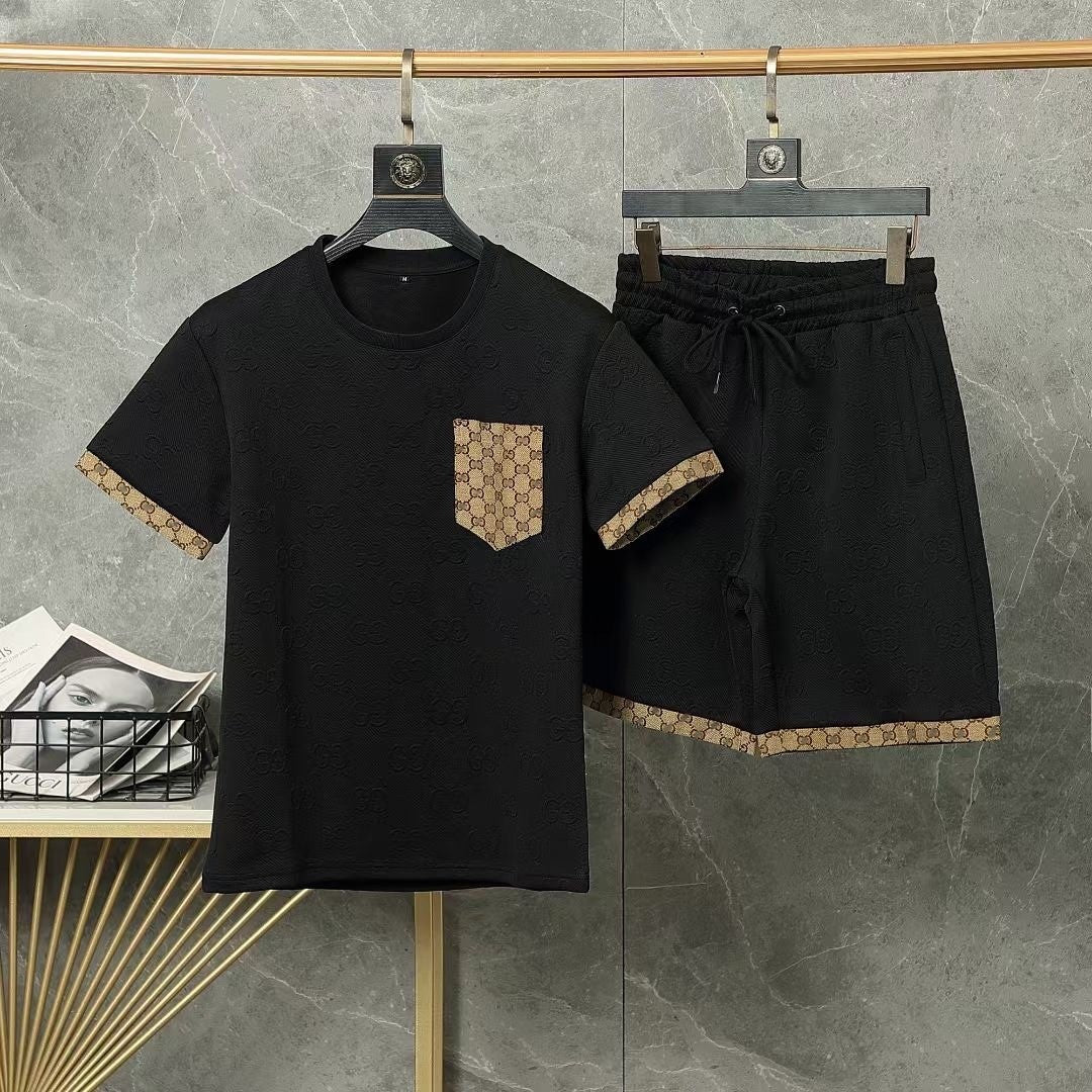 Black t-shirt and shorts set with patterned trim on hangers against a gray wall.