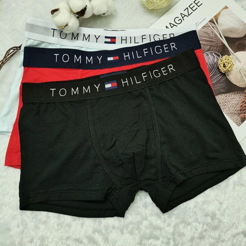 Black Tommy Hilfiger boxer briefs with branded waistbands on a textured surface.