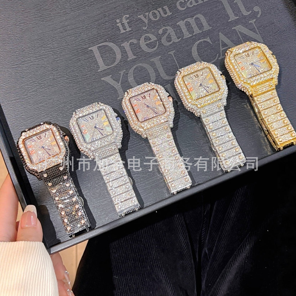 Five women's watch bracelets with rectangular crystal-encrusted cases and link-style bands are displayed in a black presentation box. The watches come in multiple metal finishes: silver, white gold, rose gold, yellow gold, and a darker bronze/brown tone.