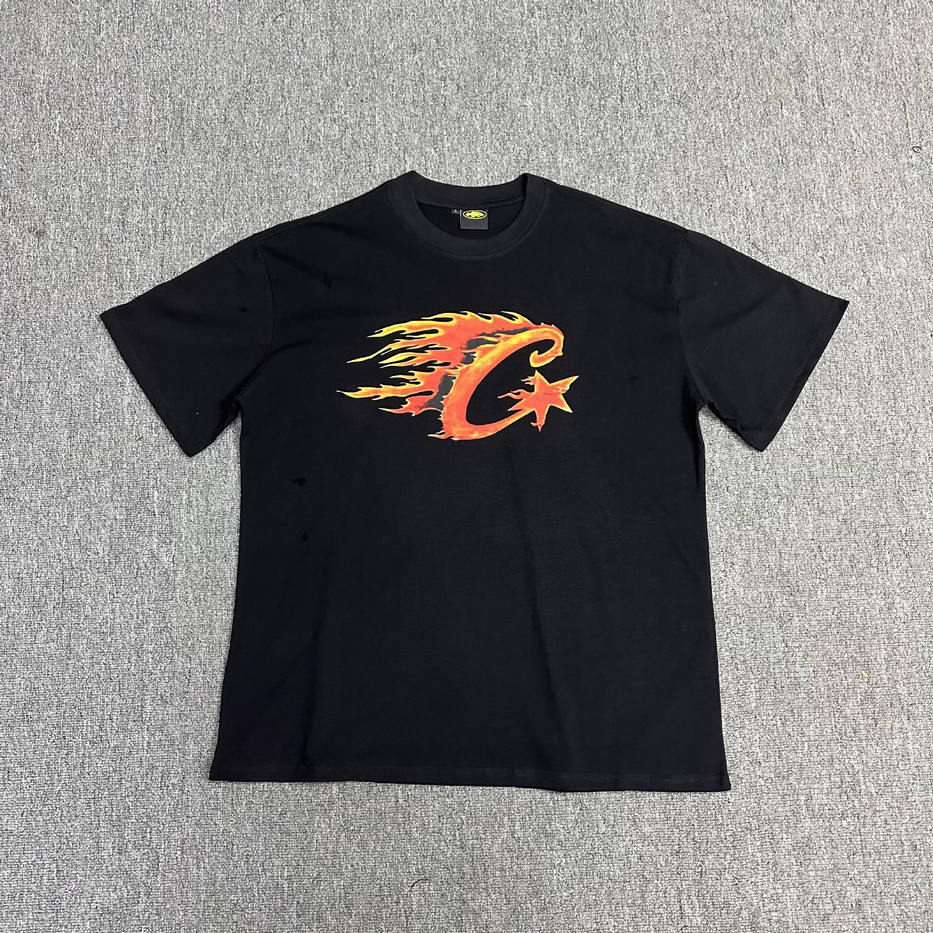 Black t-shirt with orange graphic design on a gray background
