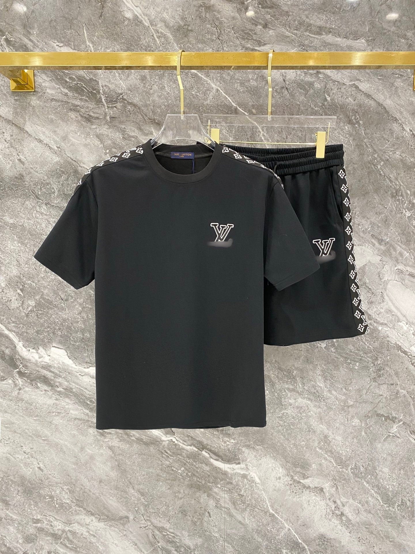 Black t-shirt and shorts set with brand logo on a marble surface