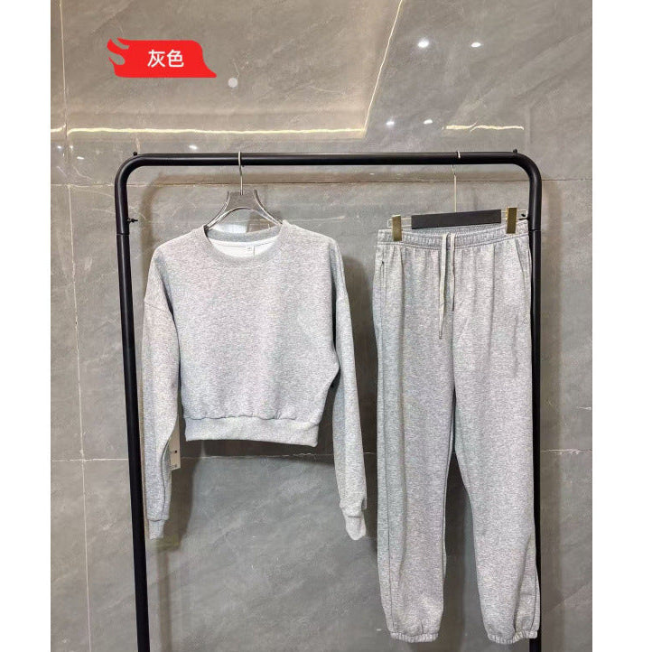 Gray sweater and pants set on a black rack against a tiled wall.