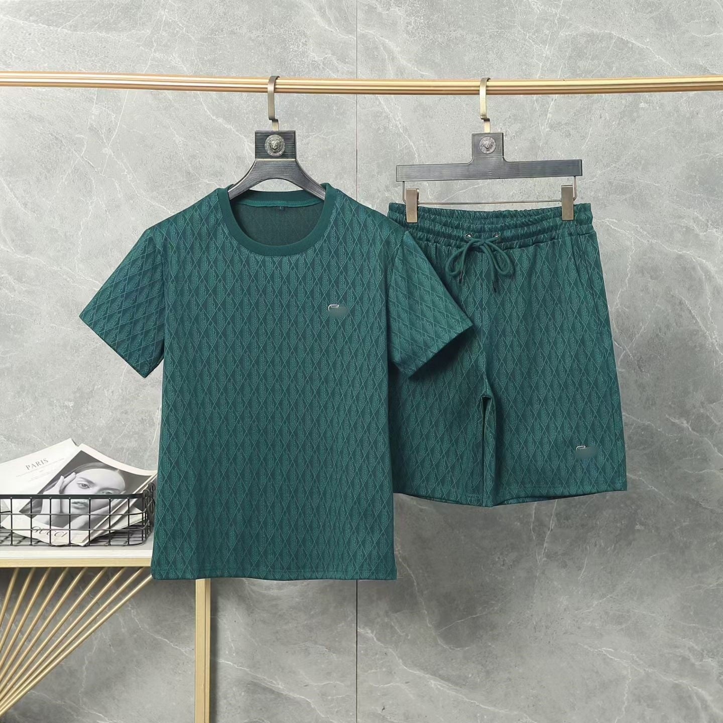 Green textured t-shirt and shorts set on hangers against a gray background