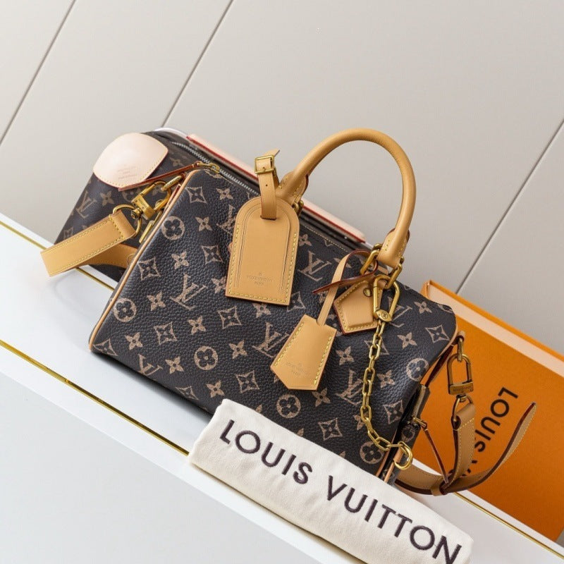 Louis Vuitton monogram handbag in dark brown coated canvas with tan leather handles and tags, displayed on a white shelf with an orange Louis Vuitton box and dust bag.