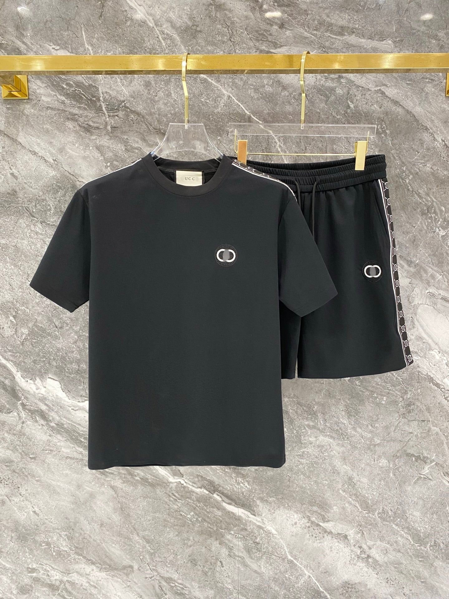 Black t-shirt and shorts set with brand logo on a marble surface