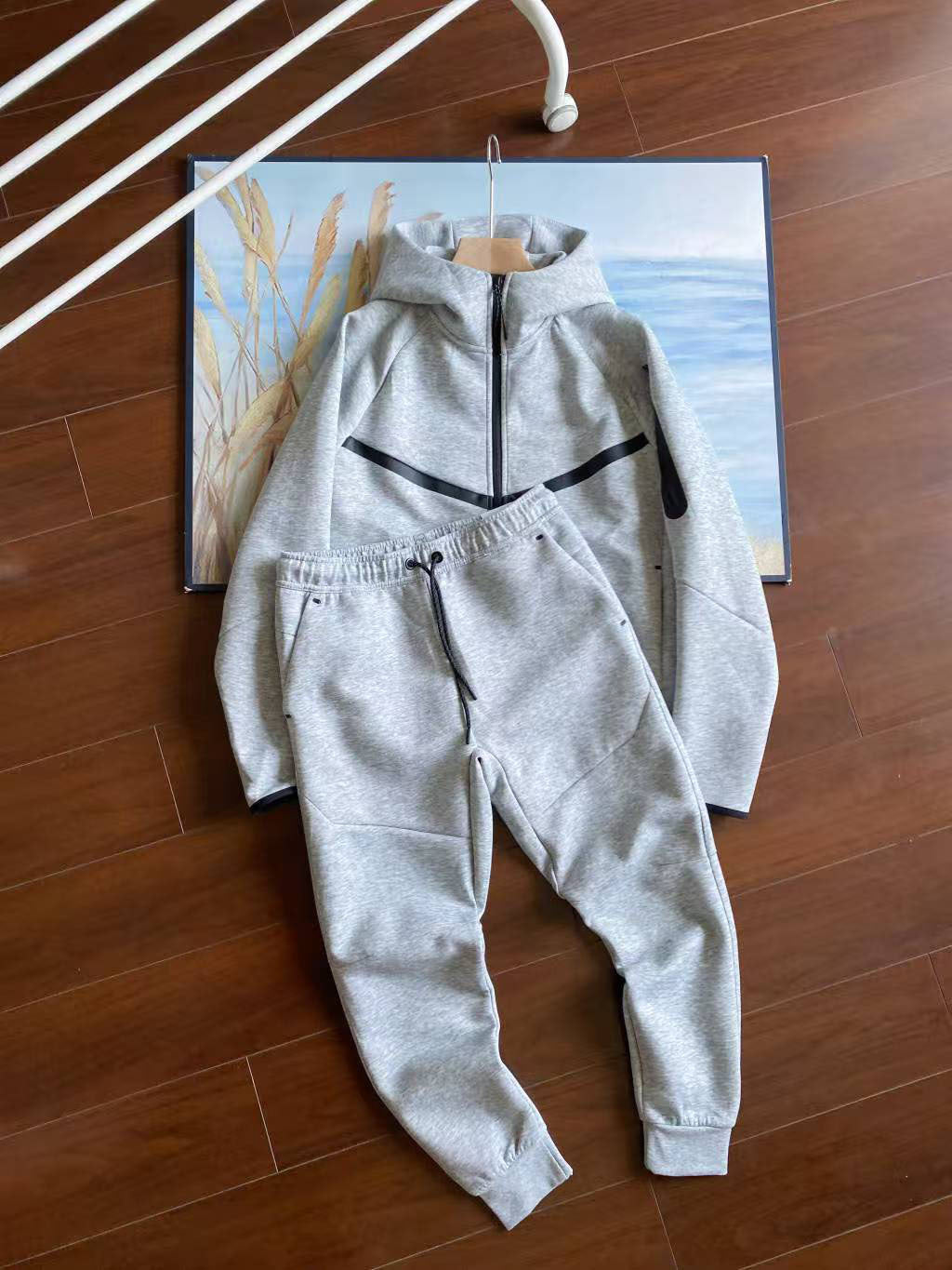 Gray tracksuit on a wooden floor with a painting in the background