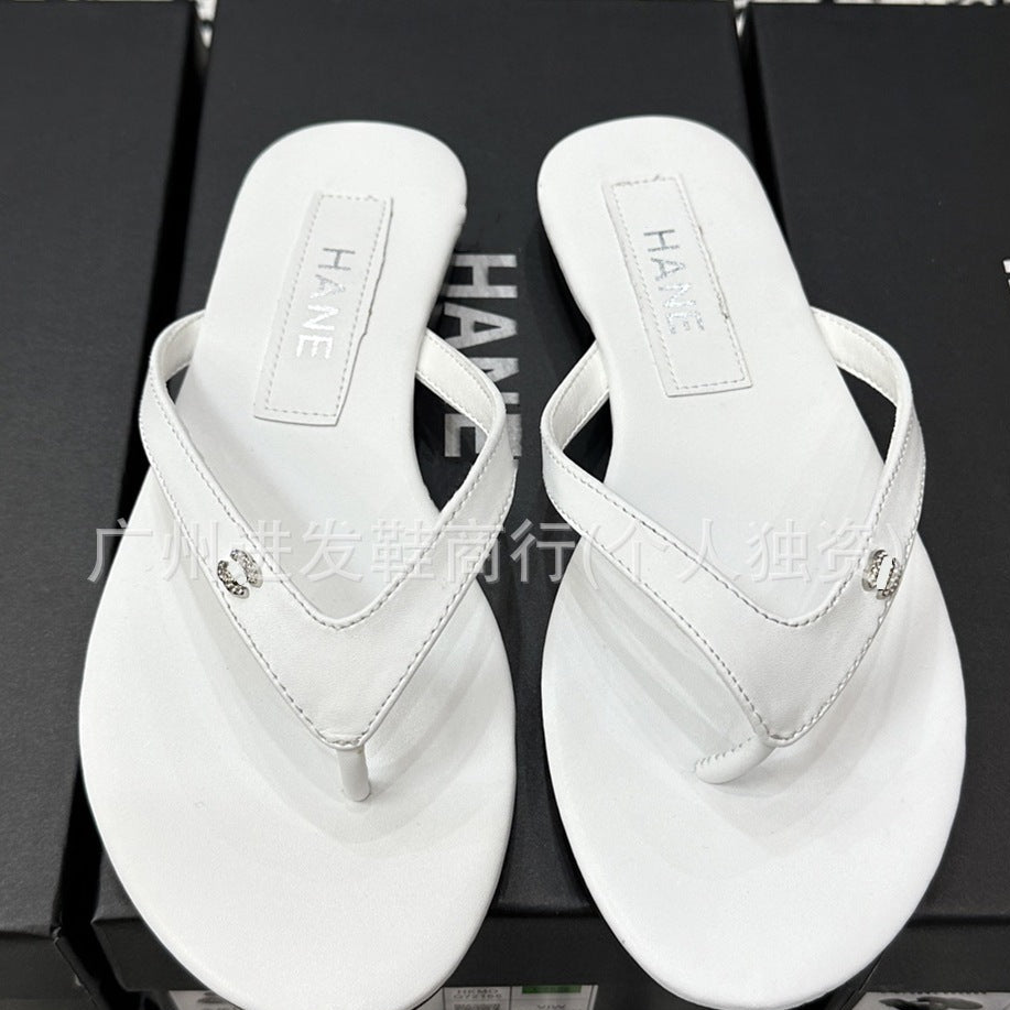 A pair of white thong sandals with small rhinestone embellishments on the straps, displayed on top of black boxes. The insoles show the brand name 'HANE'.