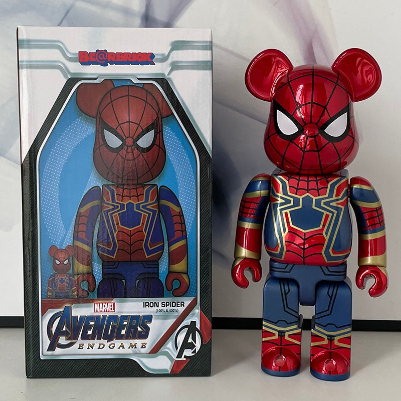 A Marvel Avengers Endgame Iron Spider Bearbrick toy figure stands next to its original window box packaging. The figure is designed like a red, blue, and gold Spider-Man bear with white eyes.
