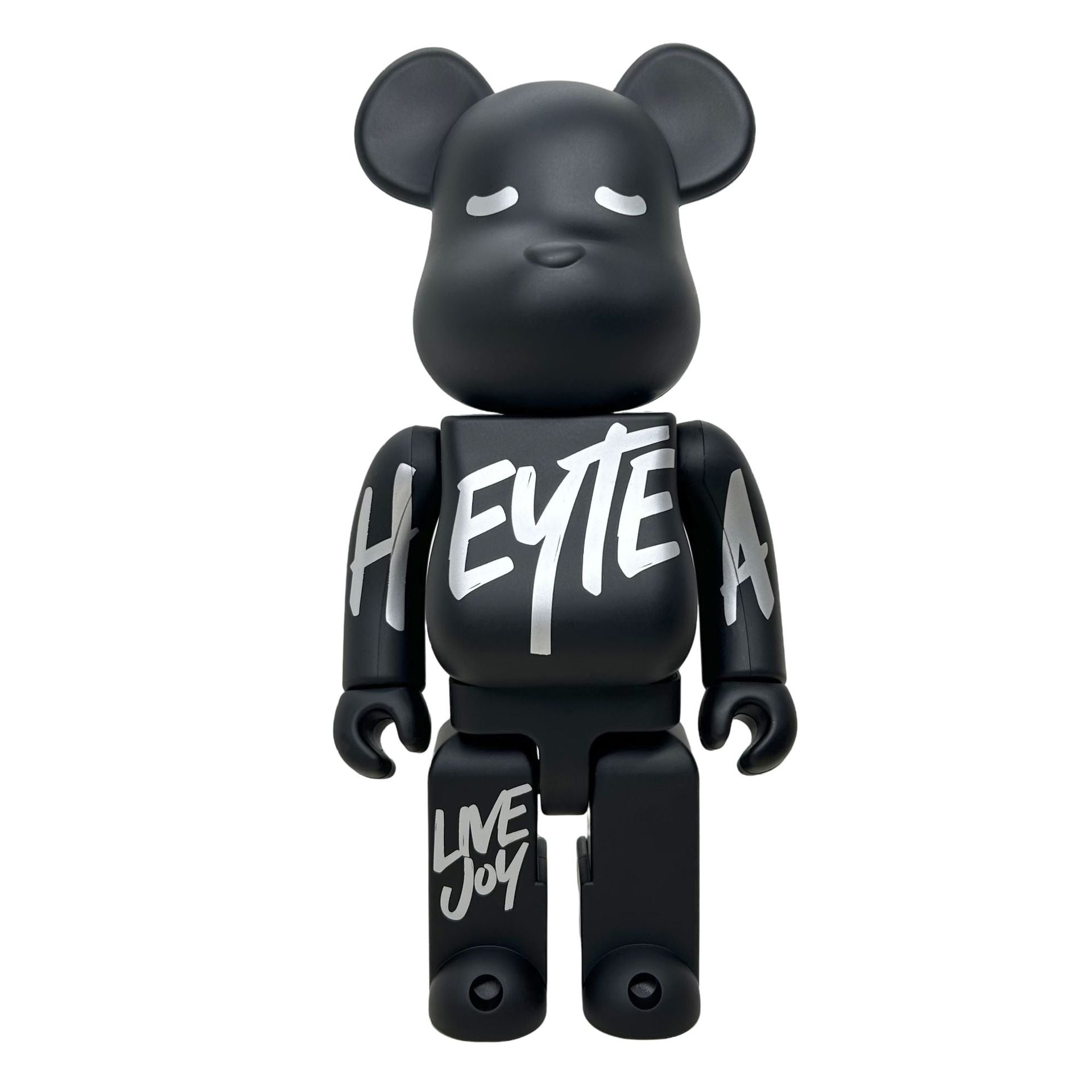 A matte black bear-shaped collectible figure with white graffiti-style text on its chest, arms, and legs, shown against a plain white background.