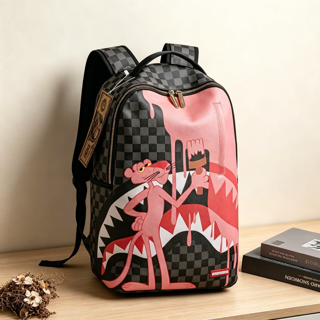 A pink and black checkered backpack featuring a graphic of the Pink Panther painting a shark mouth, displayed on a wooden table next to books.