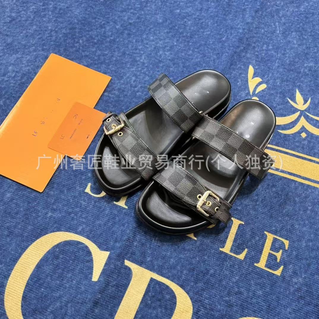 Black checkered slide sandals on a blue surface with gold text