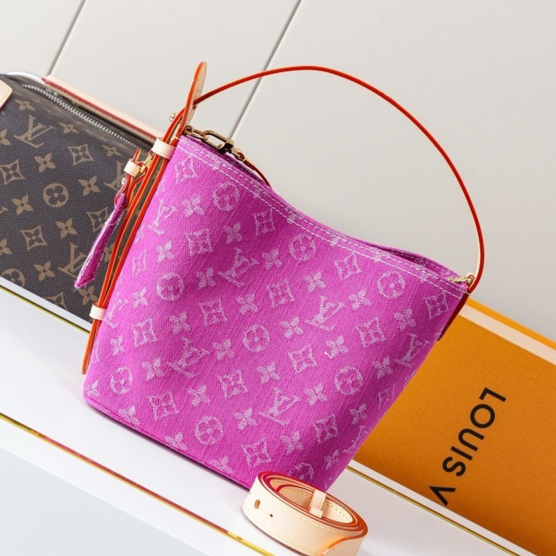 A Louis Vuitton monogram canvas bucket bag in vibrant pink, styled on a white surface next to its orange packaging box and a second monogram bag.