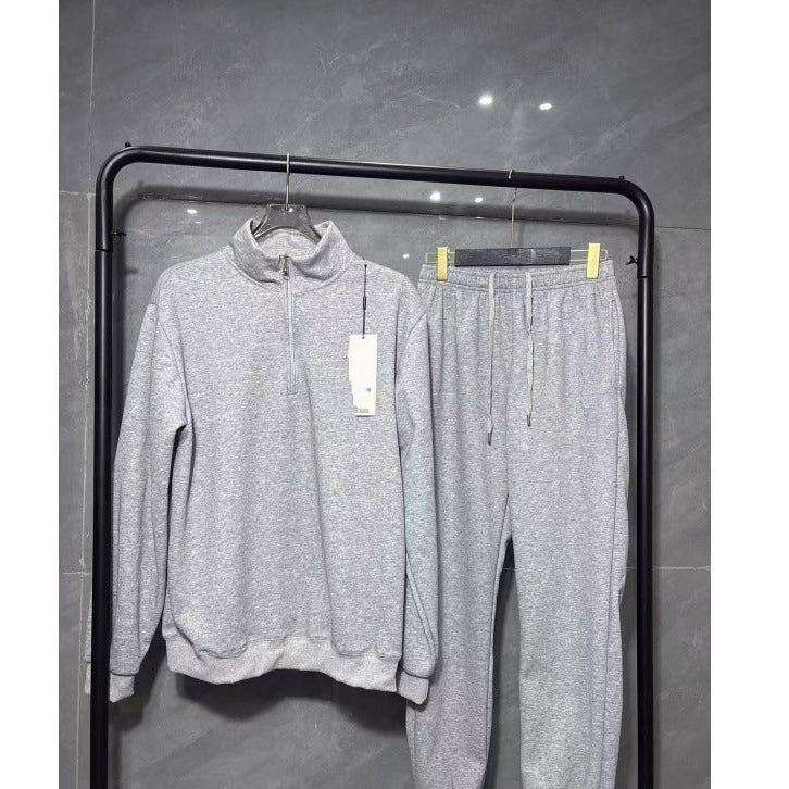 Gray tracksuit with tags on a black rack against a gray tiled wall.
