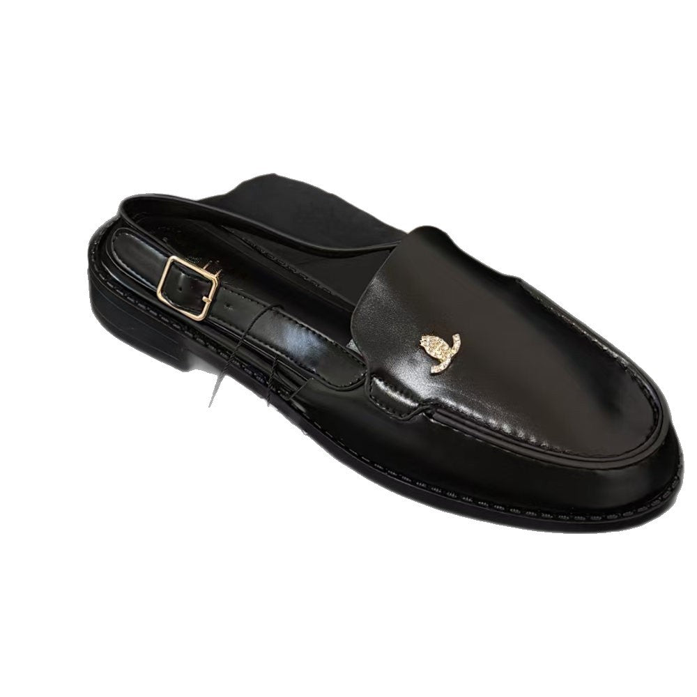 A single black leather loafer with a rear buckle strap and a small gold-tone logo emblem on the vamp, shown against a plain white background.