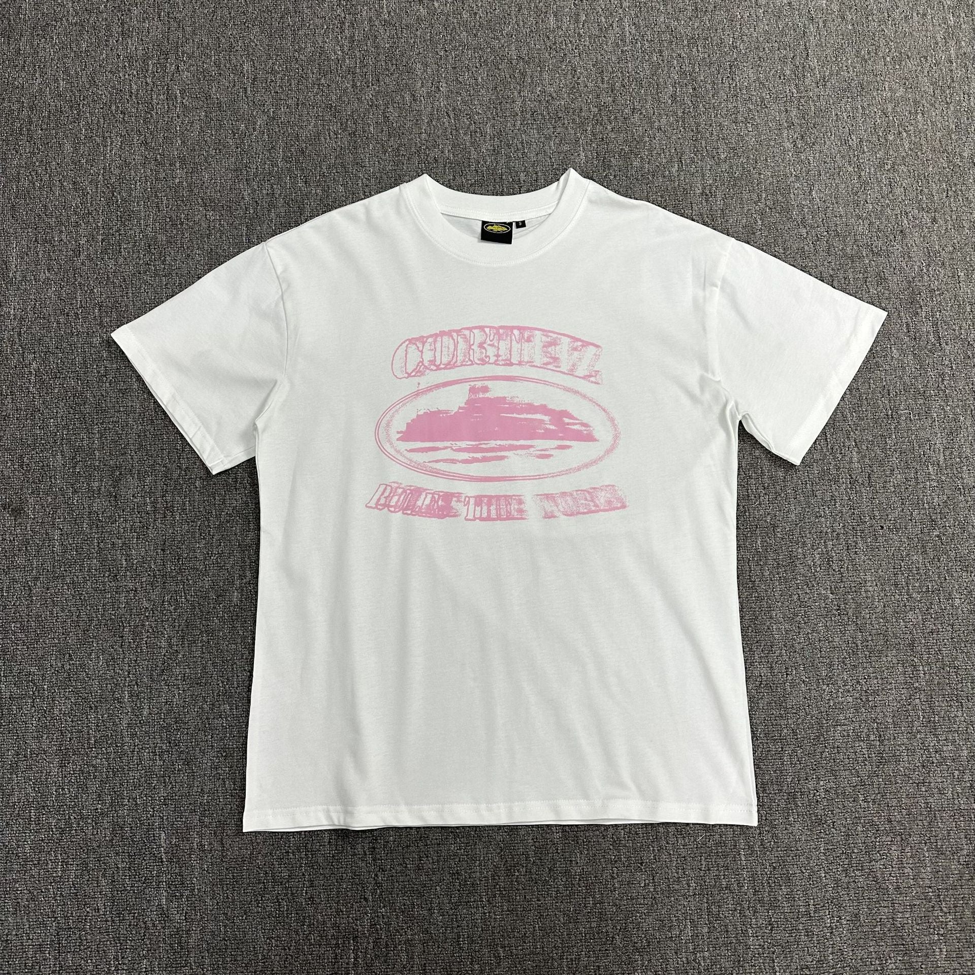 White t-shirt with pink graphic design on a gray background