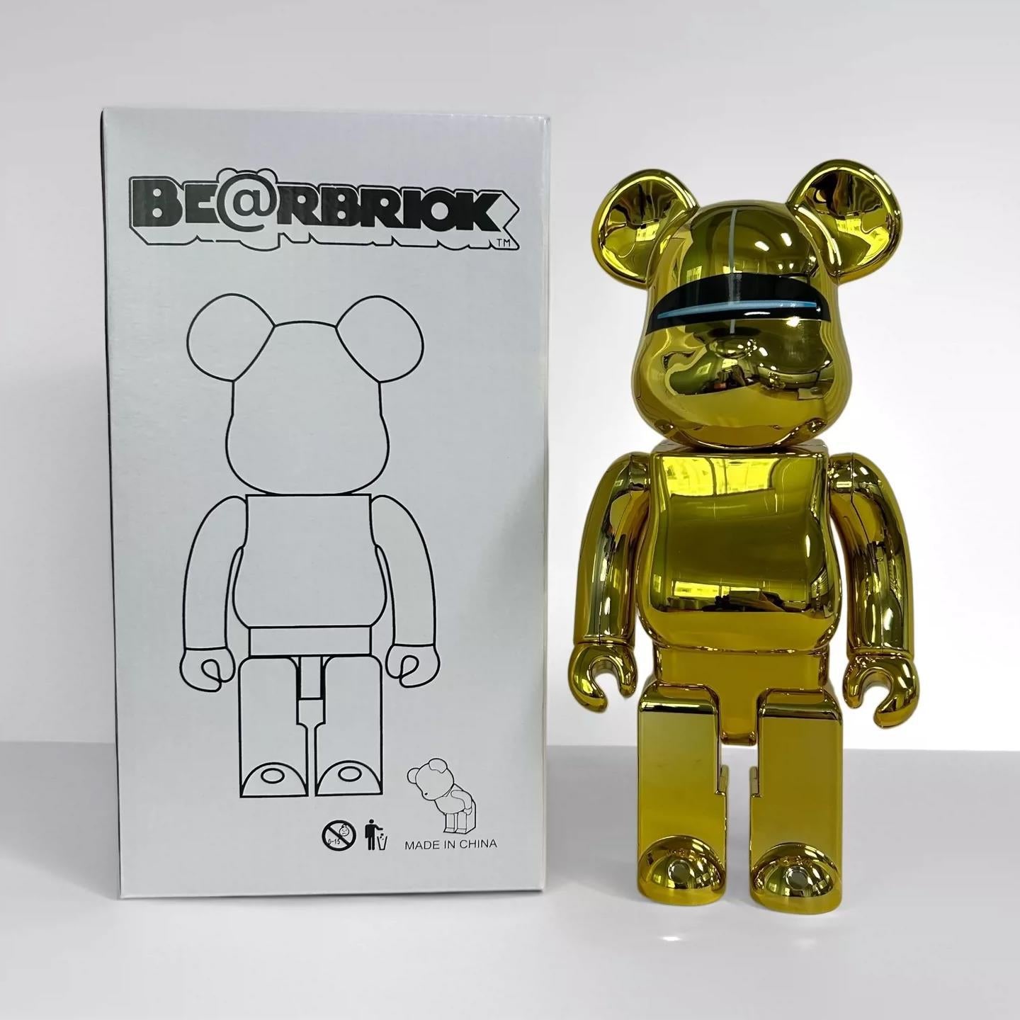 A shiny metallic gold bear-shaped collectible figure stands next to its white product box, which features the BE@RBRIOK brand name and a black line drawing of the bear figure.