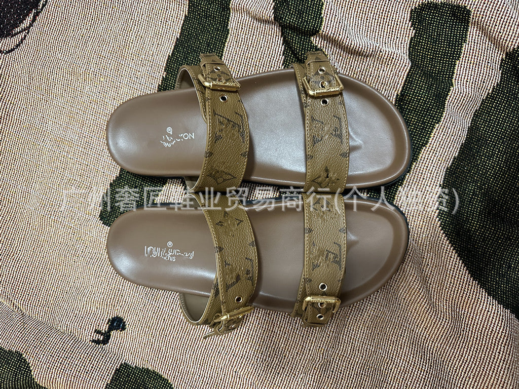 Pair of sandals with gold straps on a textured surface