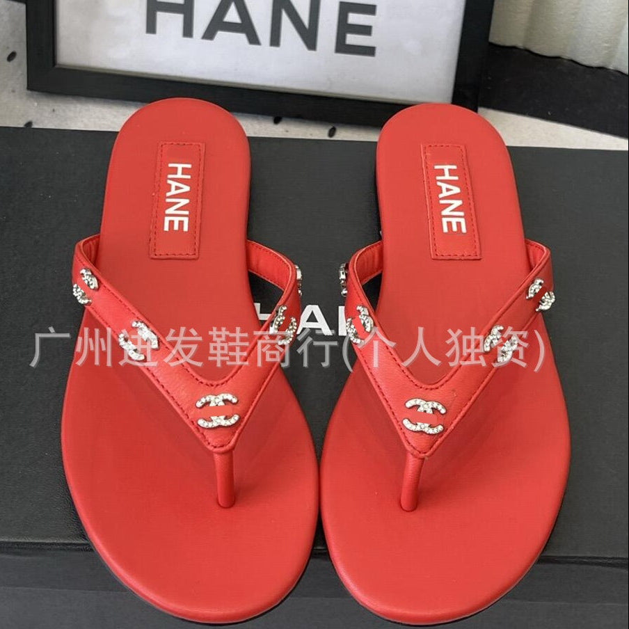 A pair of red thong sandals with silver-tone rhinestone embellishments on the straps, displayed on a black surface with a black shoebox. The brand name 'HANE' is visible on the footbeds.