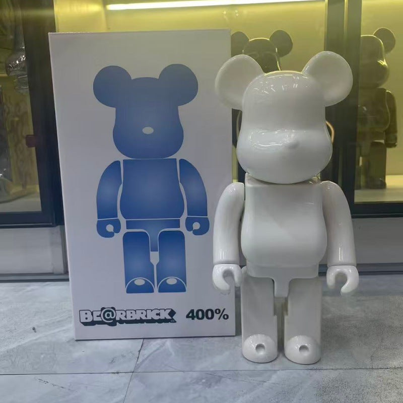 A white Bearbrick 400% bear figure standing next to its original packaging box, which features a blue bear graphic and the BE@BRICK 400% text.