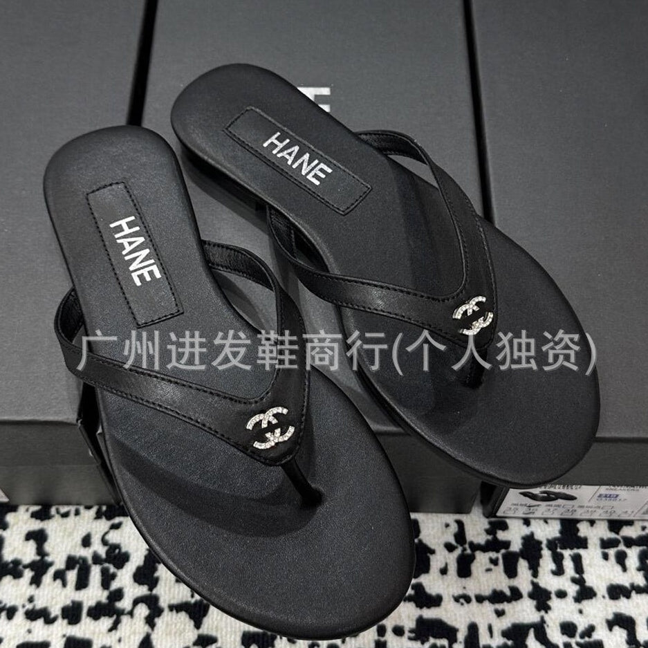 Black flip-flops with 'HANE' branding on a patterned surface.