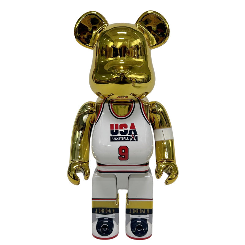 A metallic gold bear-shaped collectible figure wearing a white USA Basketball jersey with red and black details, shown against a plain white background.