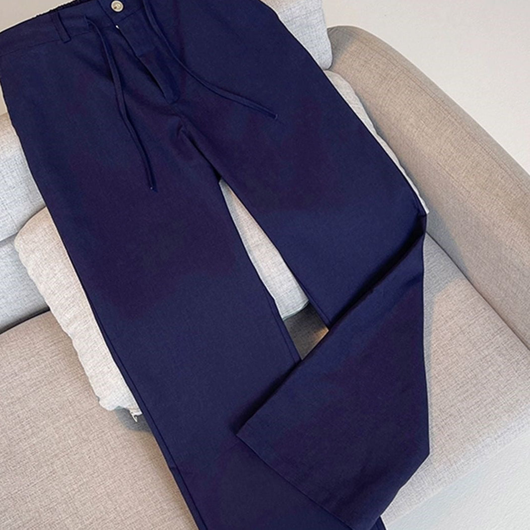 Dark navy blue wide-leg trousers with a drawstring waist and a single button closure, displayed on a light beige sofa. The image includes a top-left 'YOULIN' logo and a bottom banner with Chinese promotional text.