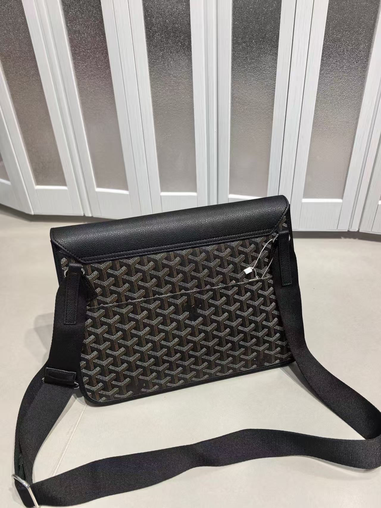 Black patterned handbag with a strap on a light surface